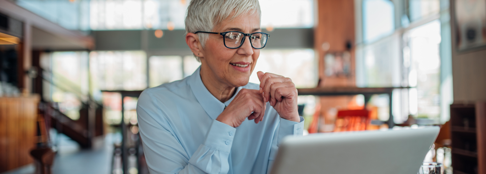 Older woman wearing glasses on a computer in a foyer